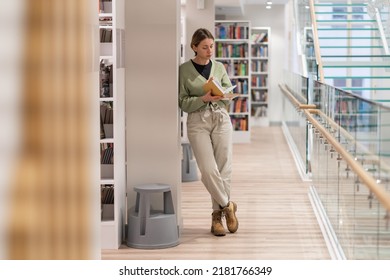Full-length of focused mature woman bookworm in library. Pensive middle-aged woman bibliophile with book enjoying reading, gaining knowledge from books, learning new skills. Lifelong Learning