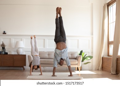 Full-length Image African Father And Little Daughter Having Fun Fool Around At Home Sportive Active Kid Girl And Dad Do Handstand Position. Funny Leisure Activities, Sporty Healthy Lifestyle Concept