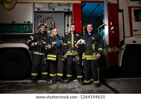 Full-length image of three fire men and woman on background of fire truck