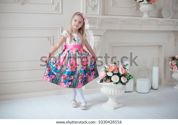 Full-length of little smiling girl child in colorful dress posing indoor.