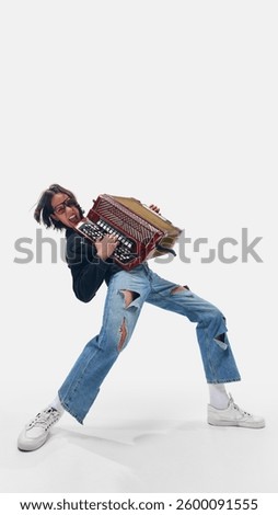 Full-length low angle view of energetic man, accordion player rocking out in ripped jeans, embracing alternative folk energy. Concept of music, artistic passion, stage energy, and performance.