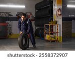 Full-length Mechanic carrying a tyre at motor garage