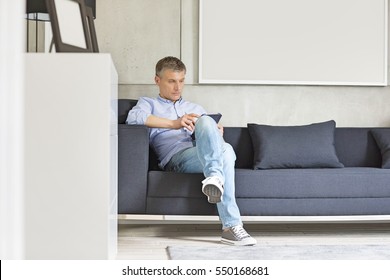 Full-length of Middle-aged man using digital tablet on sofa