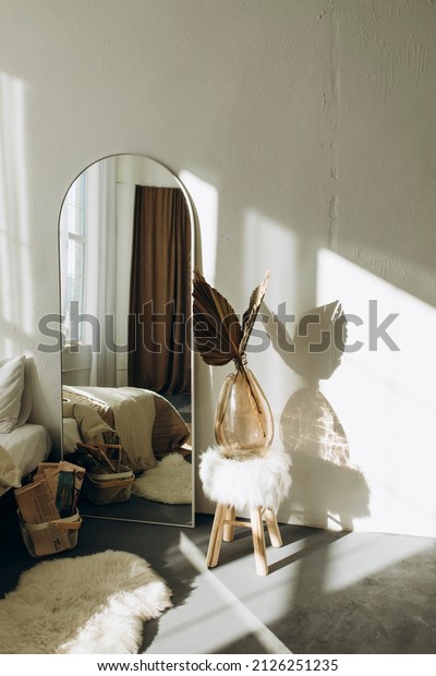 full-length mirror in the interior of a\
bright room in the style of a New York loft. details of a room with\
white walls and a large mirror. boho style\
room.