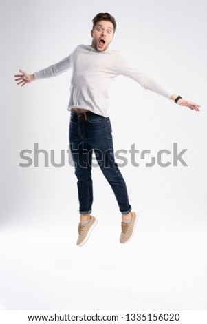 Full-length photo of funny man 30s in casual t-shirt and jeans jumping isolated over white background