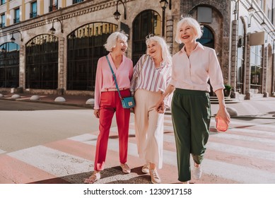 Full-length Photo Of Happy Older Women Are Walking In Center Of City While Having Fun