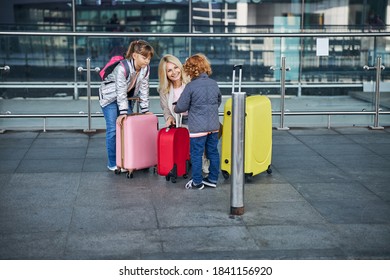 Full-length Photo Of A Loving Parent Kneeling And Talking To Her Child About Assisting Him With Carrying A Red Bag