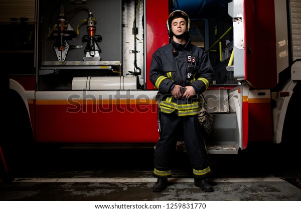 Full-length photo of man fireman on background of\
fire truck
