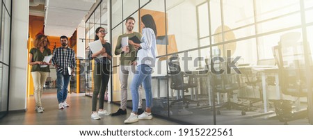 Full-length photo of positive young coworkers in office building