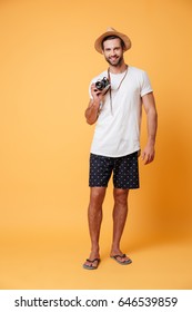 Full-length Photo Of Young Handsome Man Tourist With Retro Camera In Hands Isolated Over Yellow