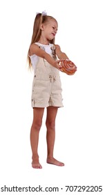 Full-length Portrait Of A Cute Little Girl With Two Ponytails, In Light Clothes, Holding A Sugary Cinnamon Bun Isolated On A White Background. A Sad, Disgusted Kid Rejecting Unhealthy Food.