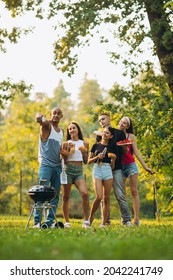 Full-length Portrait Of Five Friends Joyfully Hanging Out Together Outside City, Having Picnic, Eating Tasty Burgers, Taking Selfie On Bright Summer Day. Concept Of Summer, Party, Friendship, Fun, Ad