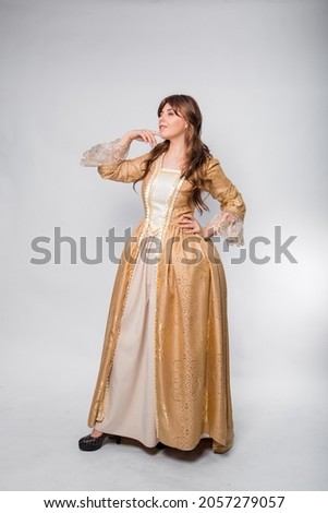 A full-length portrait of a girl in a golden rococo gown posing isolated on a white background.