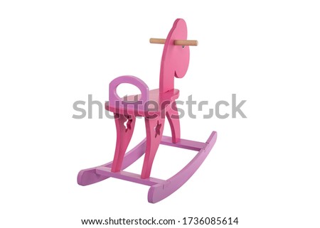 Full-length portrait of little lovely smiling girl wearing blue shirt and pink pants swaying on the wooden toy horse. Isolated on the white background