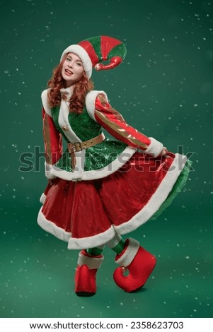 Full-length portrait of a pretty Christmas fairy elf girl in a beautiful bright costume on a green studio background. Tales for Christmas and New Year.