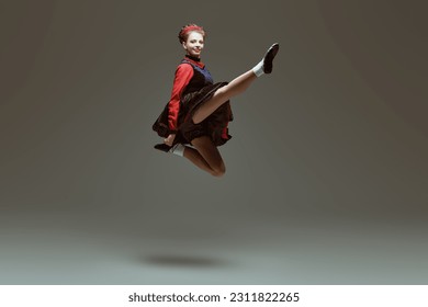 Full-length portrait of a professional dancer woman in traditional Irish dress and Ghillies soft shoes making a jump during the dance. Irish Dances. Place for text. - Shutterstock ID 2311822265