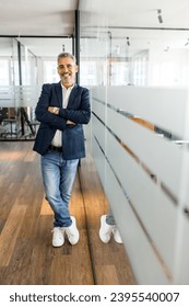 Full-length portrait of a stylish mature businessman standing in the modern office and posing against the glass partition with arms crossed, male employee, manager looking at the camera, vertical - Shutterstock ID 2395540007