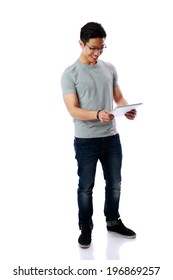 Full-length Portrait Of A Young Happy Asian Man Standing With Tablet Computer Over White Background