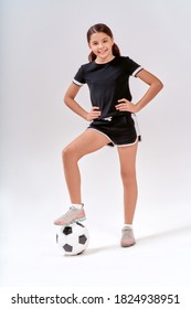 Full-length Shot Of A Cute Teenage Girl Smiling At Camera While Exercising With Soccer Ball, Isolated Over Grey Background In Studio