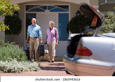 Full-length Shot Of A Senior Couple Leaving The House With Luggage And Walking Towards The Parked Car With An Open Boot On The Driveway In The Foreground.