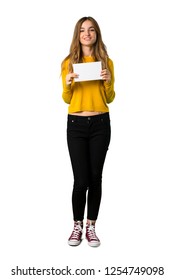 A full-length shot of a young girl with yellow sweater holding a placard for insert a concept on isolated white background - Shutterstock ID 1254749098