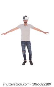 Full-length shot of young man wearing the VR glasses and spread his arms like flying, isolated on a white background.