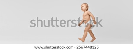 Full-length side view image of a toddler, baby girl in diaper confidently walking against studio background. Concept of childhood, health, care, parenthood. Banner. Copy space for ad