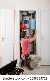 A Full-length Vertical View Of A Middle-aged Handyman Fixing Boiler In The Closet