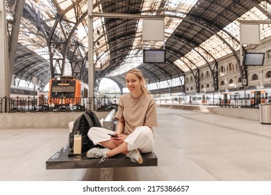 Full-length view of european blonde woman looking at camera with smile . Fair-skinned young lady sitting on the bench copy space for your advertising 