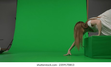 Full-size side view green screen chroma key shot of a posessed female, woman figure, ghost, poltergeist, zombie crawling over an obstacle. The ring reference. Chroma key. - Powered by Shutterstock