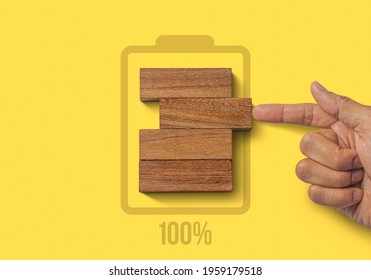 Fully charged, recharge, reboot, refresh or mindset concept. Hand putting wooden blocks with the battery charger and 100% icon on yellow background. - Powered by Shutterstock - Get 15% off with code: PIKWIZARD15