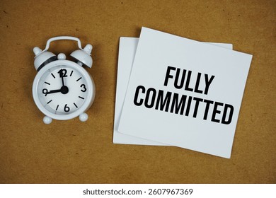 Fully Committed text on sticky note with alarm clock on paper craft background