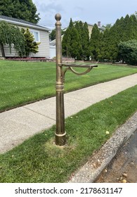 A fully constructed mailbox post next to the road in a suburban neighborhood. The actual mailbox is still missing from the base.