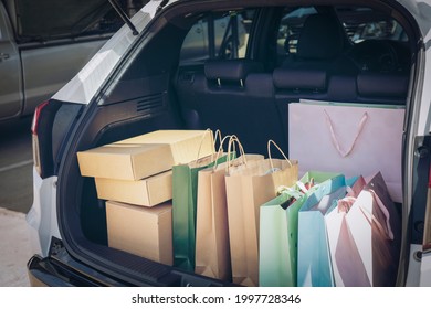 Fully Paper And Tote Shopping Bags In Cart.Colorful Bag And Brown Box In Back Car Trunk Storage. Shopping Addiction Or Shopaholic Concept.