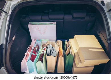 Fully Paper And Tote Shopping Bags In Cart.Colorful Bag And Brown Box In Back Car Trunk Storage. Shopping Addiction Or Shopaholic Concept.