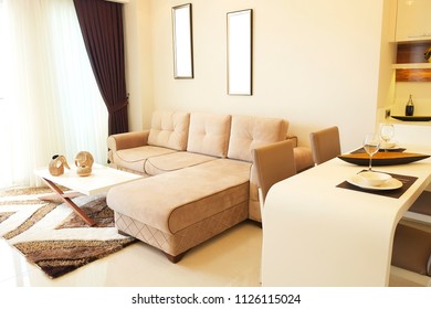 Fully stacked open plan kitchen living room, minimal modern design interior apartment. White furniture, upholstery. Counter w tableware, table settings, oven, sofa, shelves, decor elements. Background