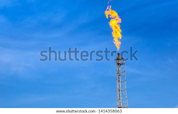 fume of fire on flare stack to burning\
heat gas, pollution in environment, for power and safety in\
petrochemical, chemical refinery or power plant in industrial zone,\
blue sky, global warming\
concept