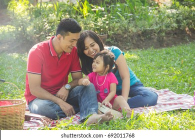 Fun Asian Family Having A Picnic In A Park Outdoors Portrait