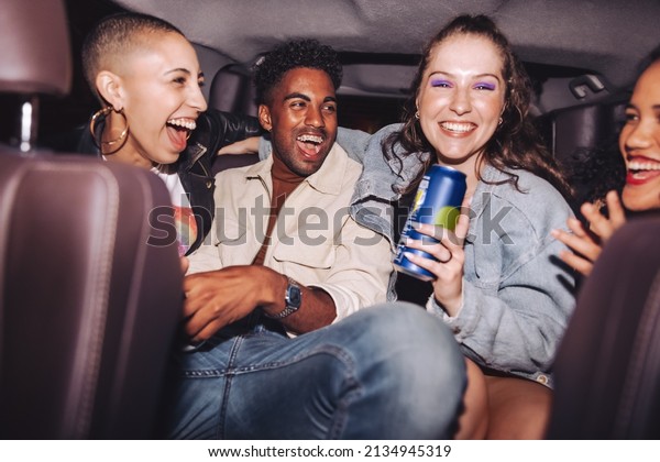 Fun\
in the back seat. Group of four happy friends laughing together\
while sitting together in the back of a car. Carefree friends\
having a good time in their ride home after a\
party.