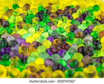 fun background: many colorful transparent beads swollen in water of the hydrogel lie side by side on a white surface, close, short focus - Powered by Shutterstock