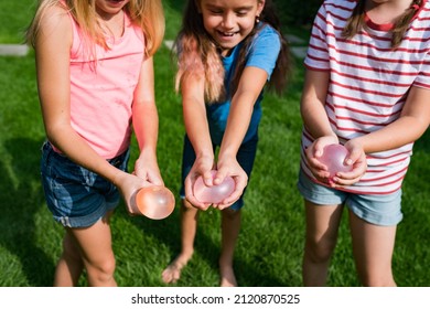 Fun Backyard Water Balloons Games For Kids. Happy Girls Toss The Water Balloon From One Person To The Other. Water Balloon Fight On Hot Summer Day