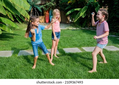 Fun Baqckyard Water Balloons Games For Kids. Happy Girls Toss The Water Balloon From One Person To The Other. Water Balloon Fight On Hot Summer Day