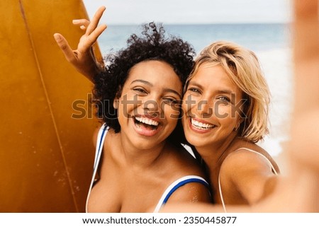 Fun beach memories are made as female surfers flash bright smiles for a selfie, encapsulating the carefree spirit and the thrilling experiences of their unforgettable surfing trip.