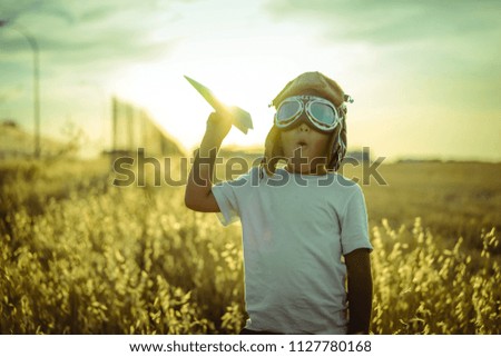Fun, boy at sunset playing at being aviator, he wears pilot glasses of airplanes and some cardboard like wings