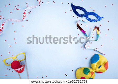 Fun carnival decoration on blue background with space for text. Carnival elements with masks, glasses, clown tie, glitter