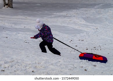 Fun In The City Park.  Little Girl Pulls Up Mountain Inflatable Mountain Descent Seat