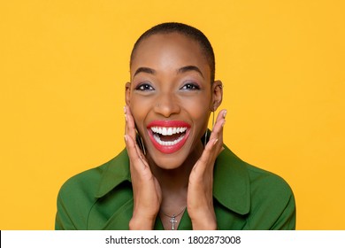 Fun close up portrait of Happy African American woman laughing with open palms in isolated studio yellow background