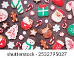 Fun colorful Christmas cookie background against dark stone. Top view. Holiday baking concept.