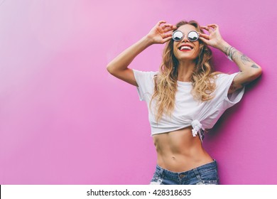 Fun and colorful. Young pretty happy woman in shorts posing against pink wall.