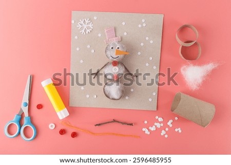 Fun craft project with a snowman made from various materials like cotton stuffing, buttons, and twigs. Suitable for holiday decorations, craft supplies, or children activity-based businesses. creative
